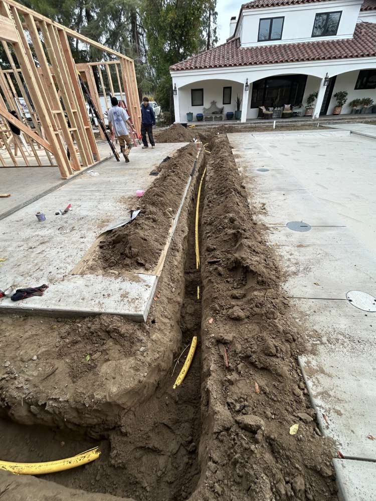 Professional installation of a high-durability yellow poly gas line within a deep, precisely excavated trench for a residential new construction project, ensuring safe and reliable energy delivery.