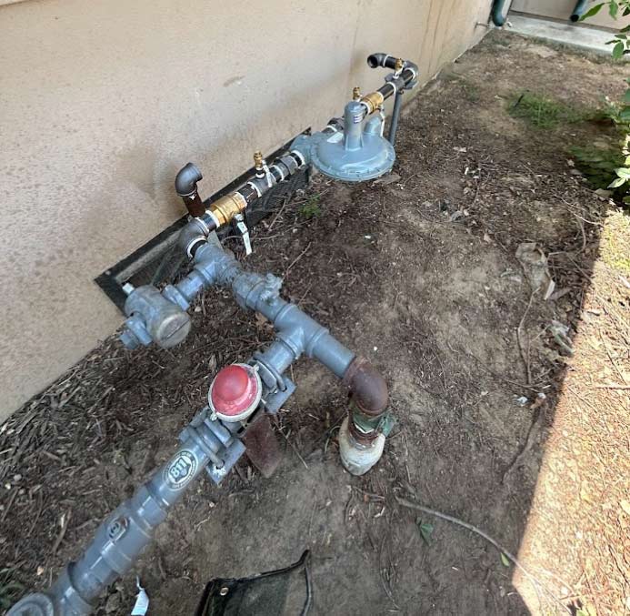 A robust outdoor gas meter and piping assembly installed with precision against a residential exterior, demonstrating high-quality safety standards and durable utility connections.