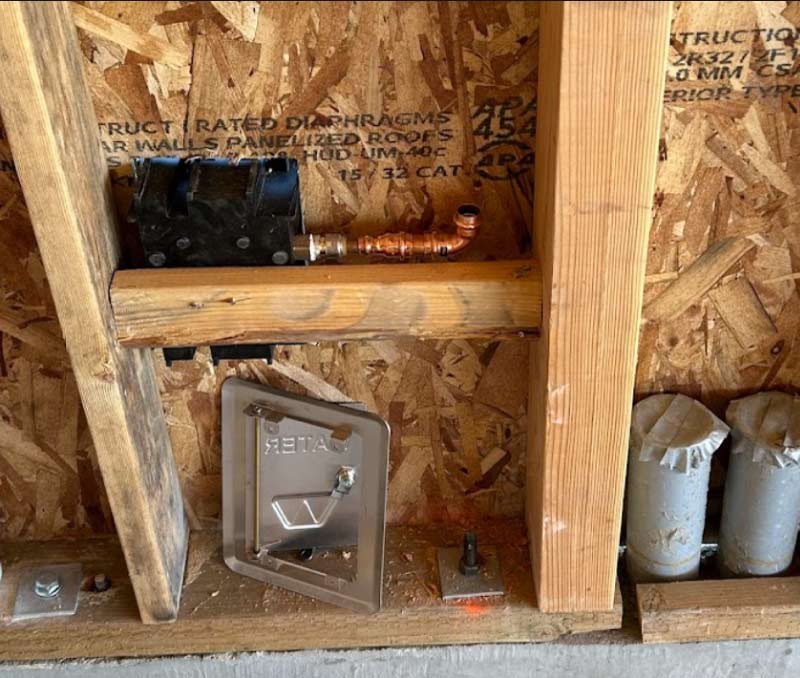 Detailed rough-in plumbing stage featuring expertly installed copper fittings and secure valve housing within a new residential wall frame.